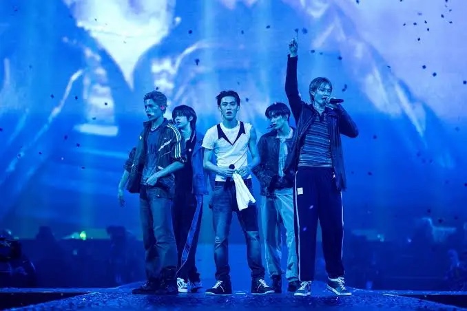 CORTIS performing on a blue-lit stage with confetti