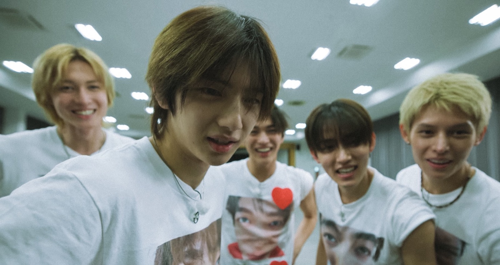 Keonho of CORTIS leaning into the camera with the other four members behind him